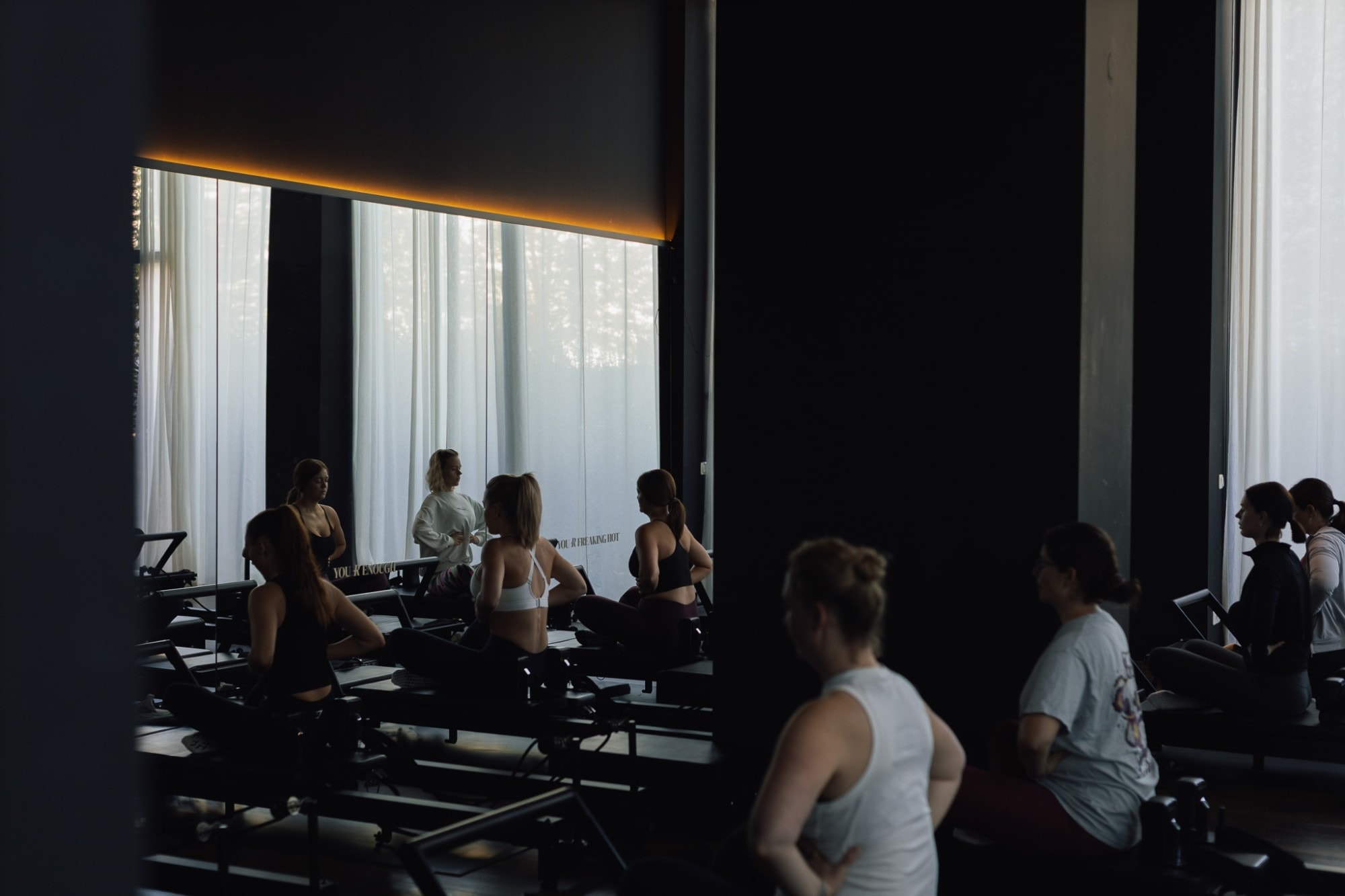Eine Class auf dem Reformer, die Trainerin erklärt vor der Spiegelwand eine Übung